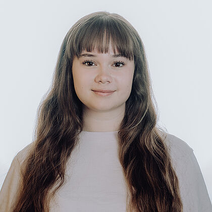 Eine junge Frau mit langen Haaren lächelt in die Kamera.